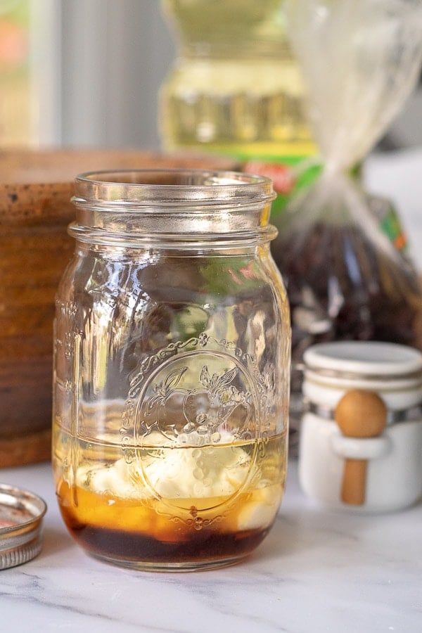 the ingredients for maple dressing in a glass ball jar