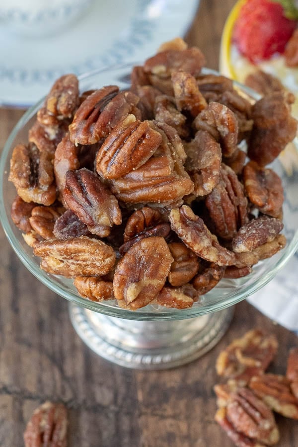 an overhead shot of candied pecans in an antique silver bowl