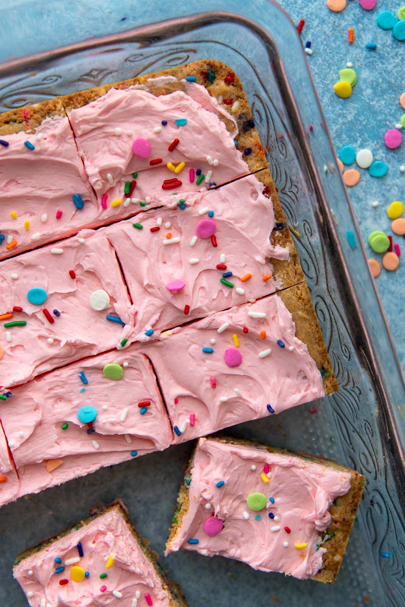 cut cookie bars with pink icing in a 9X13 pan