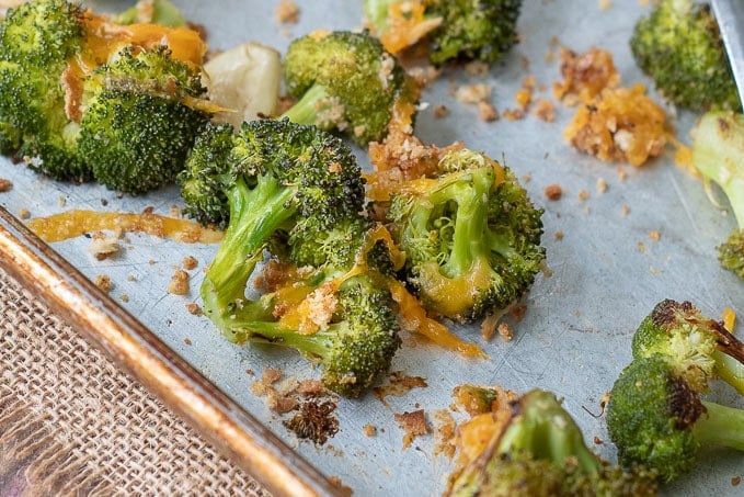a close up of roasted broccoli and cheese on a baking sheet