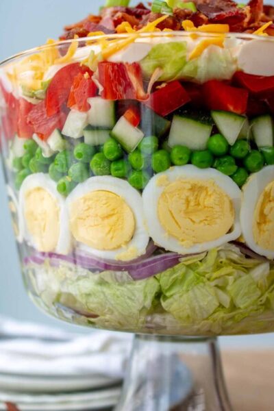 close up of 7 layer salad layers in a glass trifle bowl