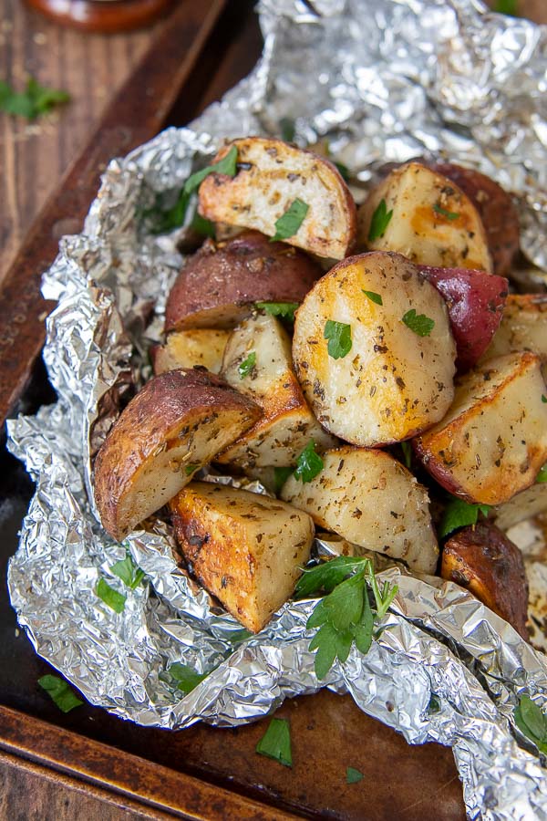 a close up of grilled red potatoes in an opened foil packet