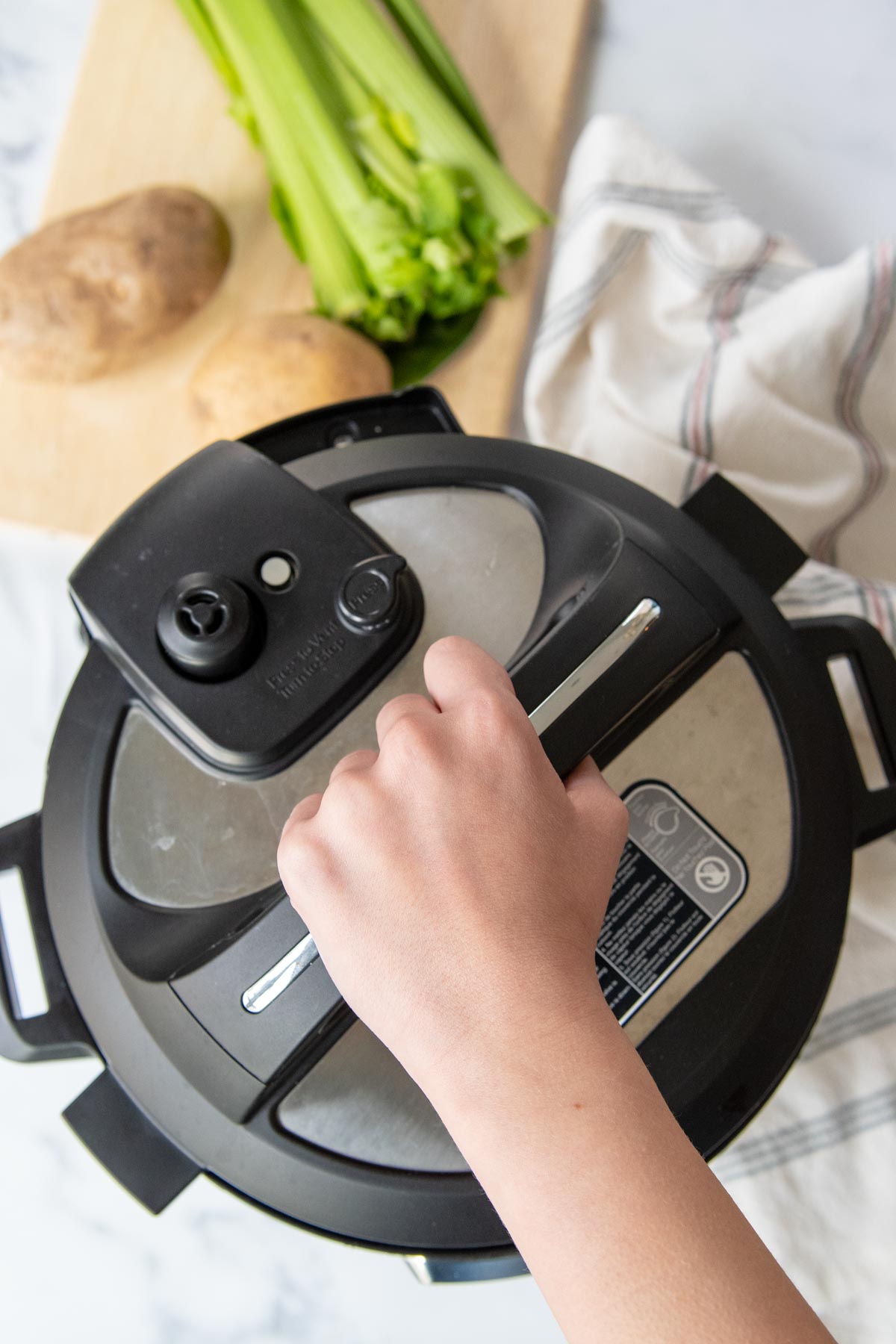 a hand opening a pressure cooker