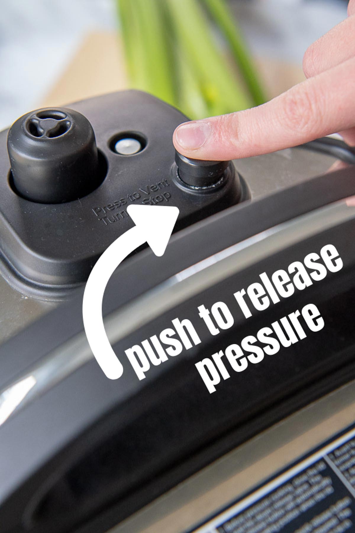 a finger pushing a pressure cooker seal valve