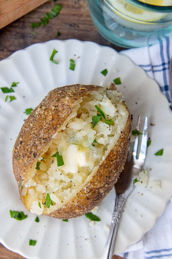 an overhead shot of an instant pot baked potato split open with melting butter in the middle