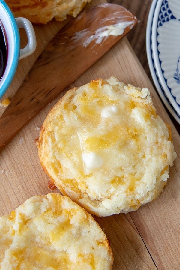 a gluten free cheese biscuit sliced open with butter spread on