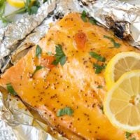 grilled salmon nested in foil with lemon slices laying on top