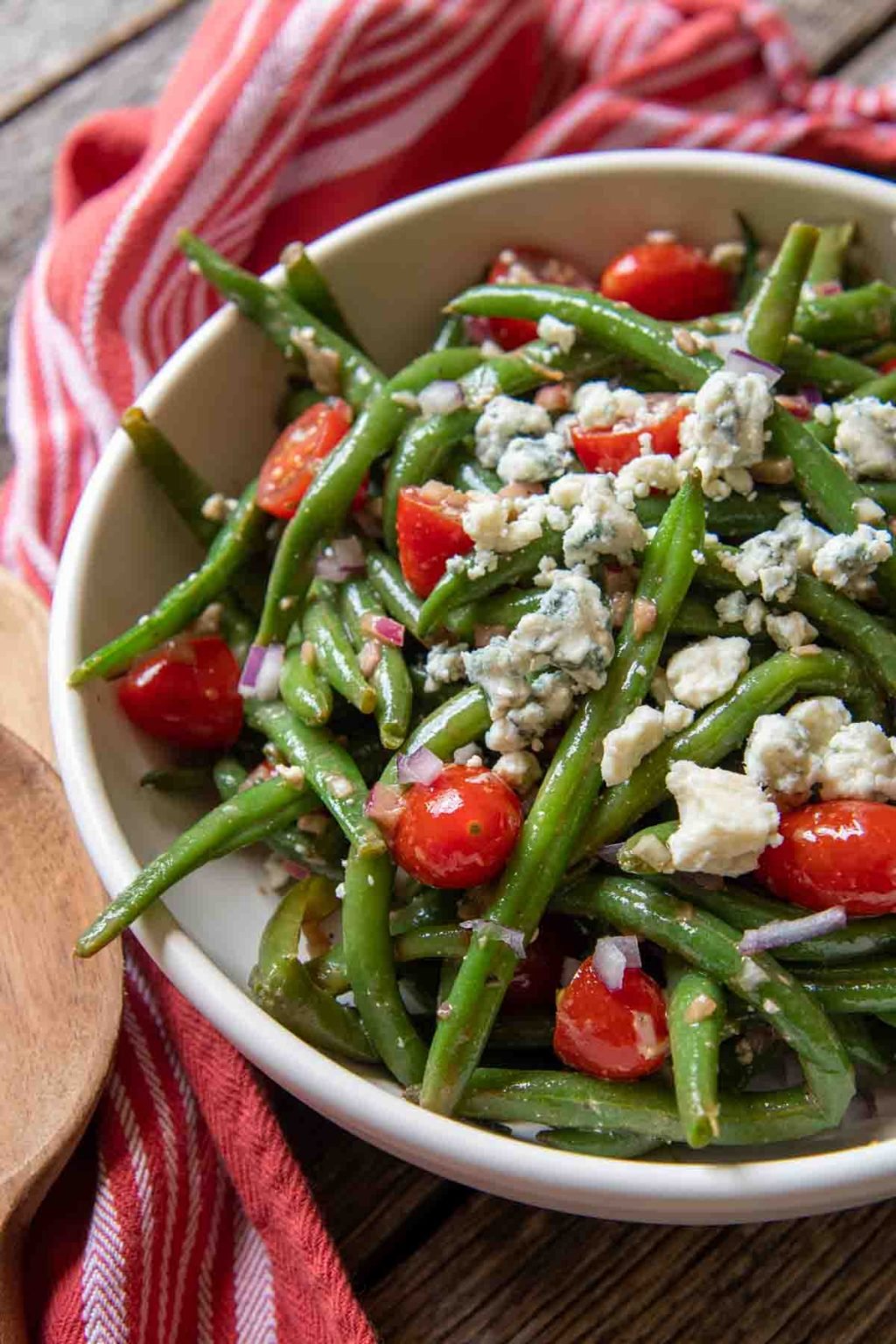 a close up of a serving bowl of beans, blue cheese and tomatoes