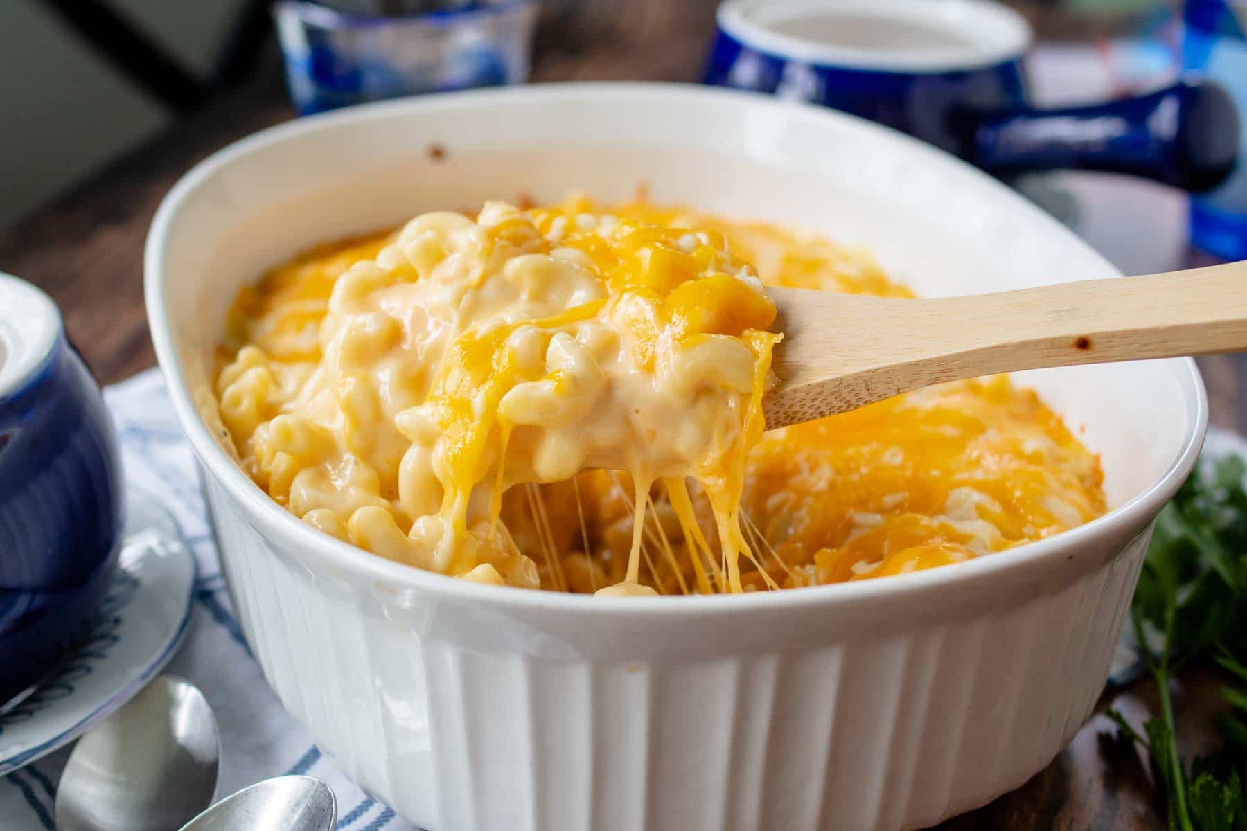 casserole dish with a wooden spoon scooping out mac and cheese