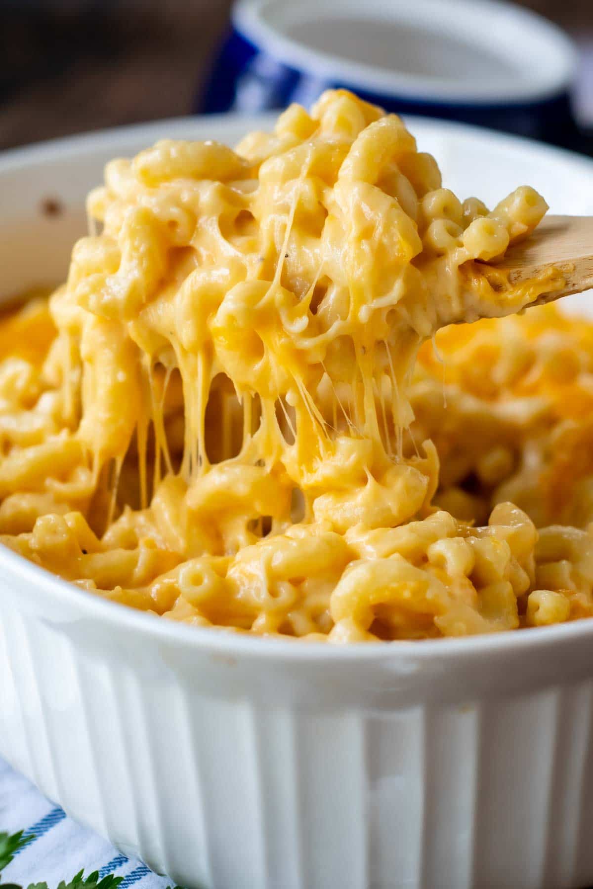 a wooden spoon lifting out cheesy baked velveeta mac and cheese
