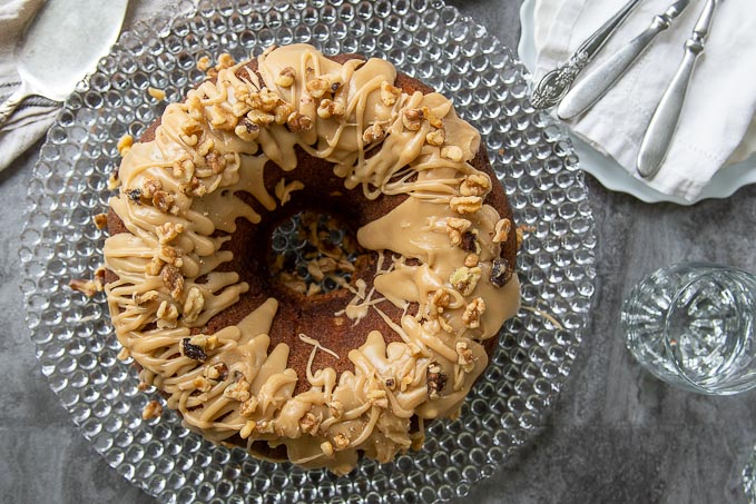 overhead shot of an apple bundt cake with glaze and nuts drizzled on top