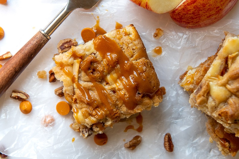 a sliced apple bar on waxed paper with caramel sauce drizzled over it