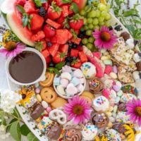 photo a dessert platter on a white tray with fruit, sweets, and fresh flowers