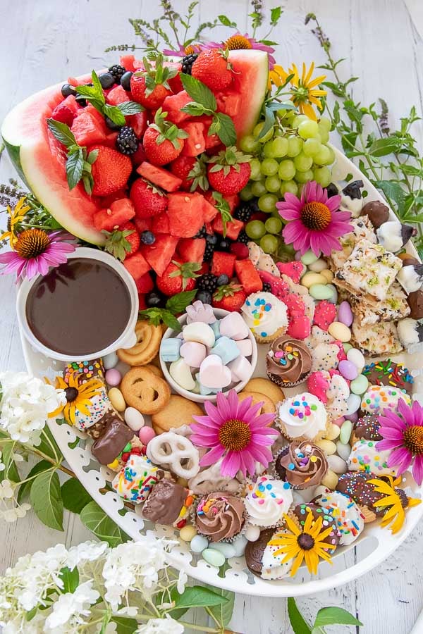 photo a dessert platter on a white tray with fruit, sweets, and fresh flowers