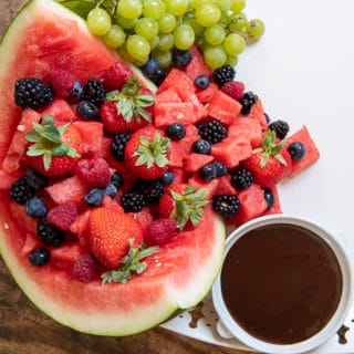close up of watermelon on dessert board with a cup of chocolate next to it