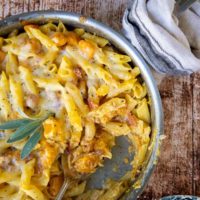 an overhead shot of butternut squash pasta bake in a skillet with cheese on top