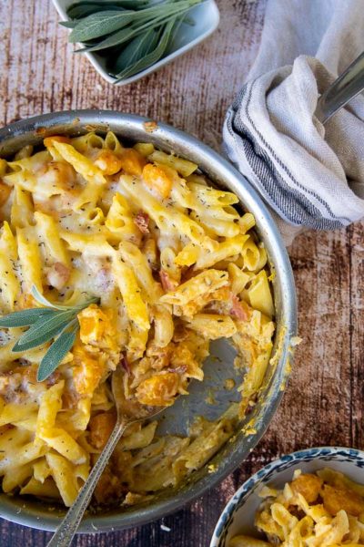 an overhead shot of butternut squash pasta bake in a skillet with cheese on top
