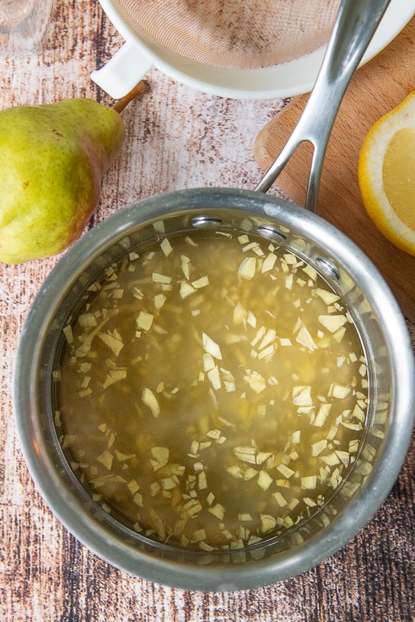 a pan of ginger syrup with fresh chopped ginger inside