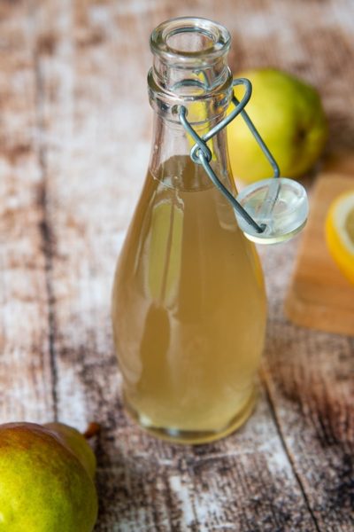 a bottle of ginger simple syrup in a glass bottle with a fresh pear next to it