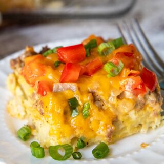 a slice of breakfast casserole on a white plate with green onions.