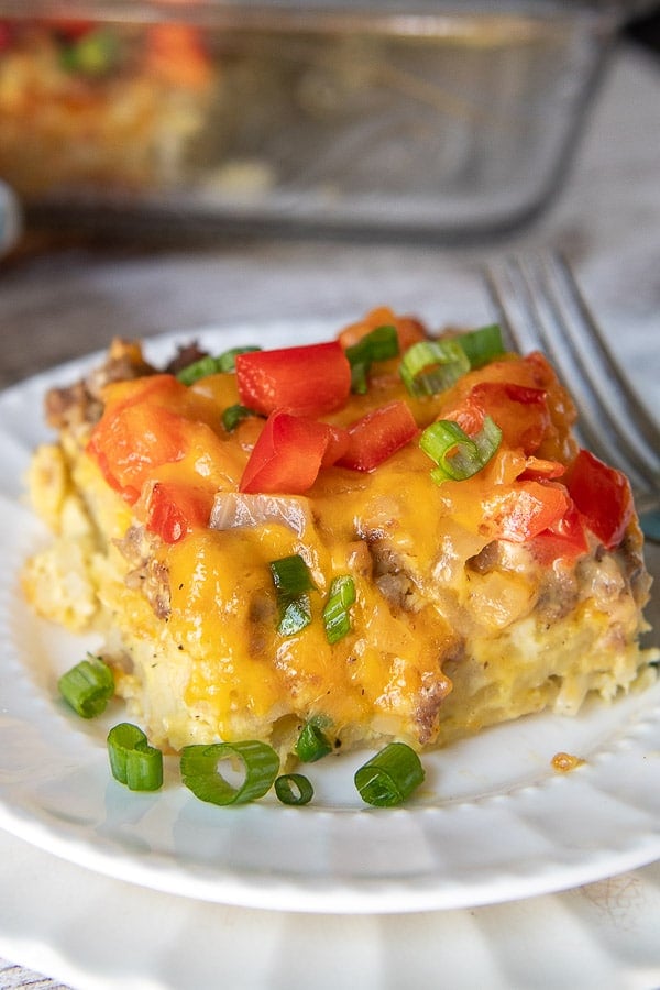 a breakfast casserole on a white plate with melted cheese over top