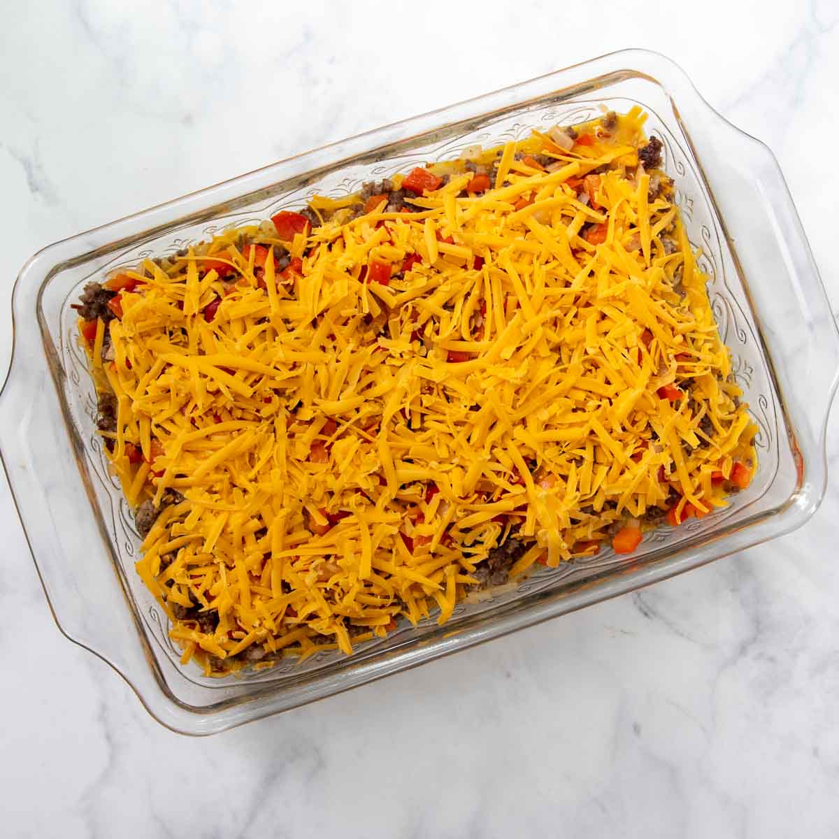 unbaked casserole with cheese on top.