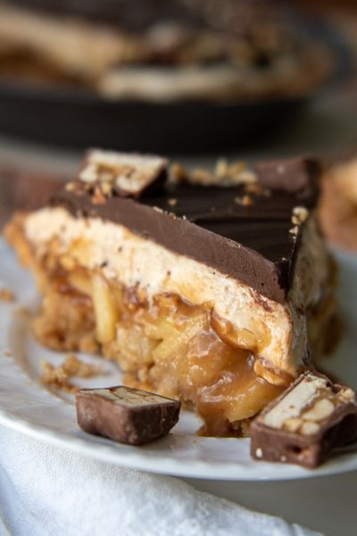 snickers pie on a white plate with sliced snickers around