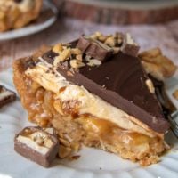 a slice of snickers pie on a white plate with caramel apple filling