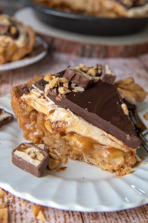 a slice of snickers pie on a white plate with caramel apple filling
