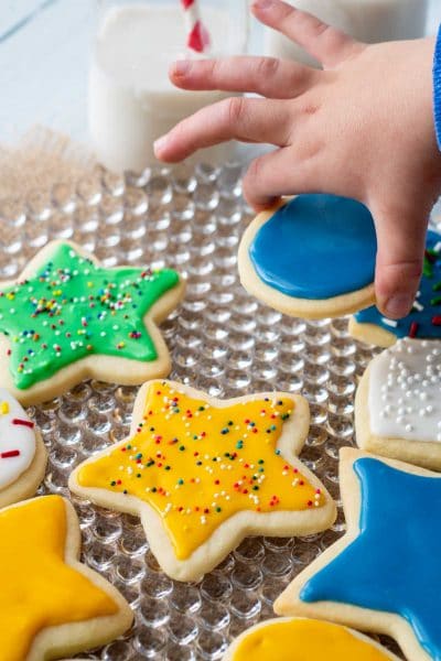 a child's hand picking up a decorated sugar cookie