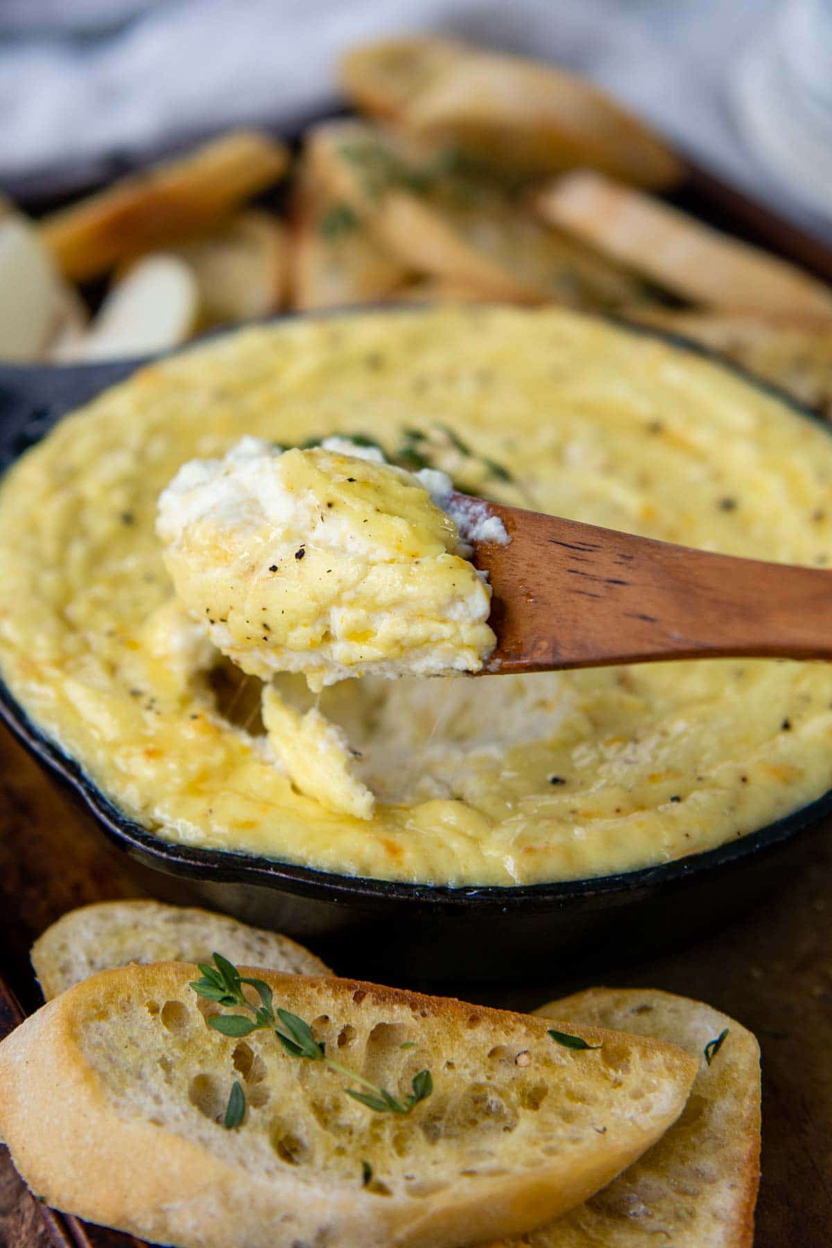 a wooden spoon holding up some ricotta dip