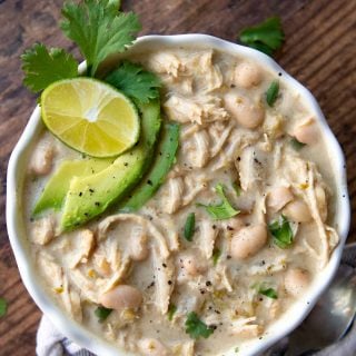 overhead shot of instant pot white chicken chili with sliced avocados, cilantro, and lime wedge on top