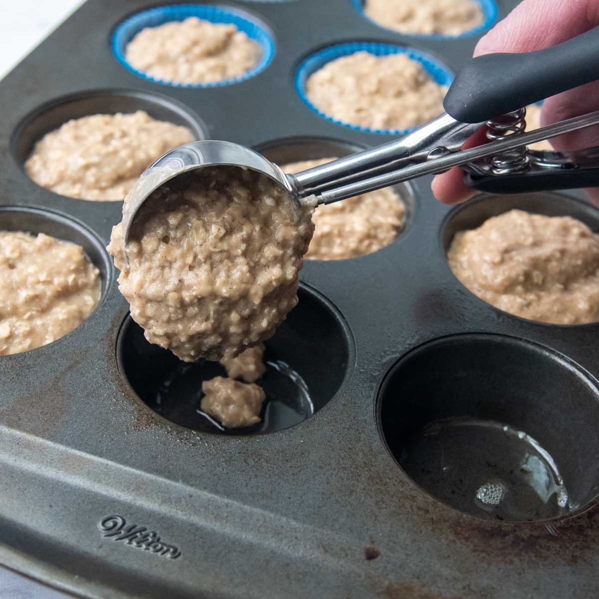 trigger scoop dropping muffin batter into tins.