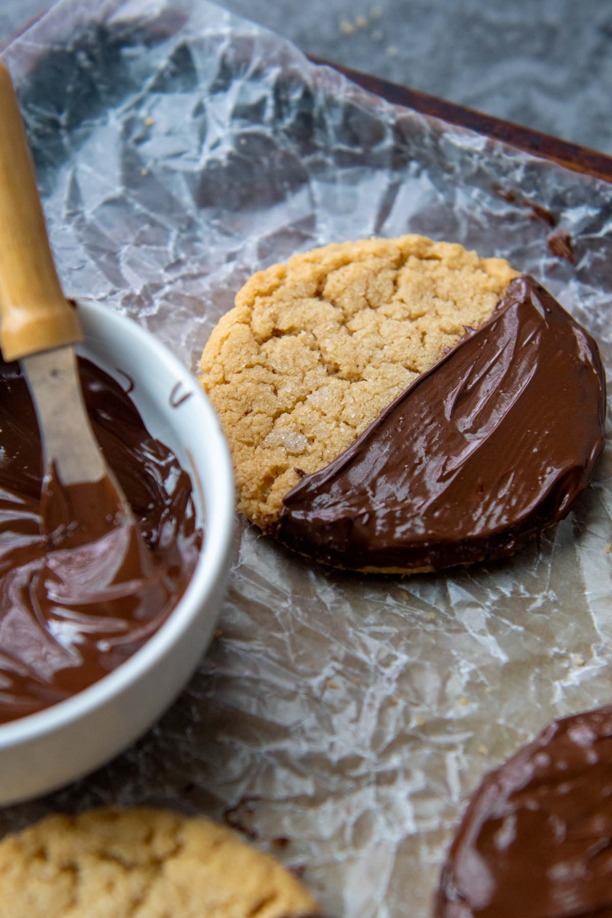 chocolate dipped peanut butter cookie with melted chocolate next to it