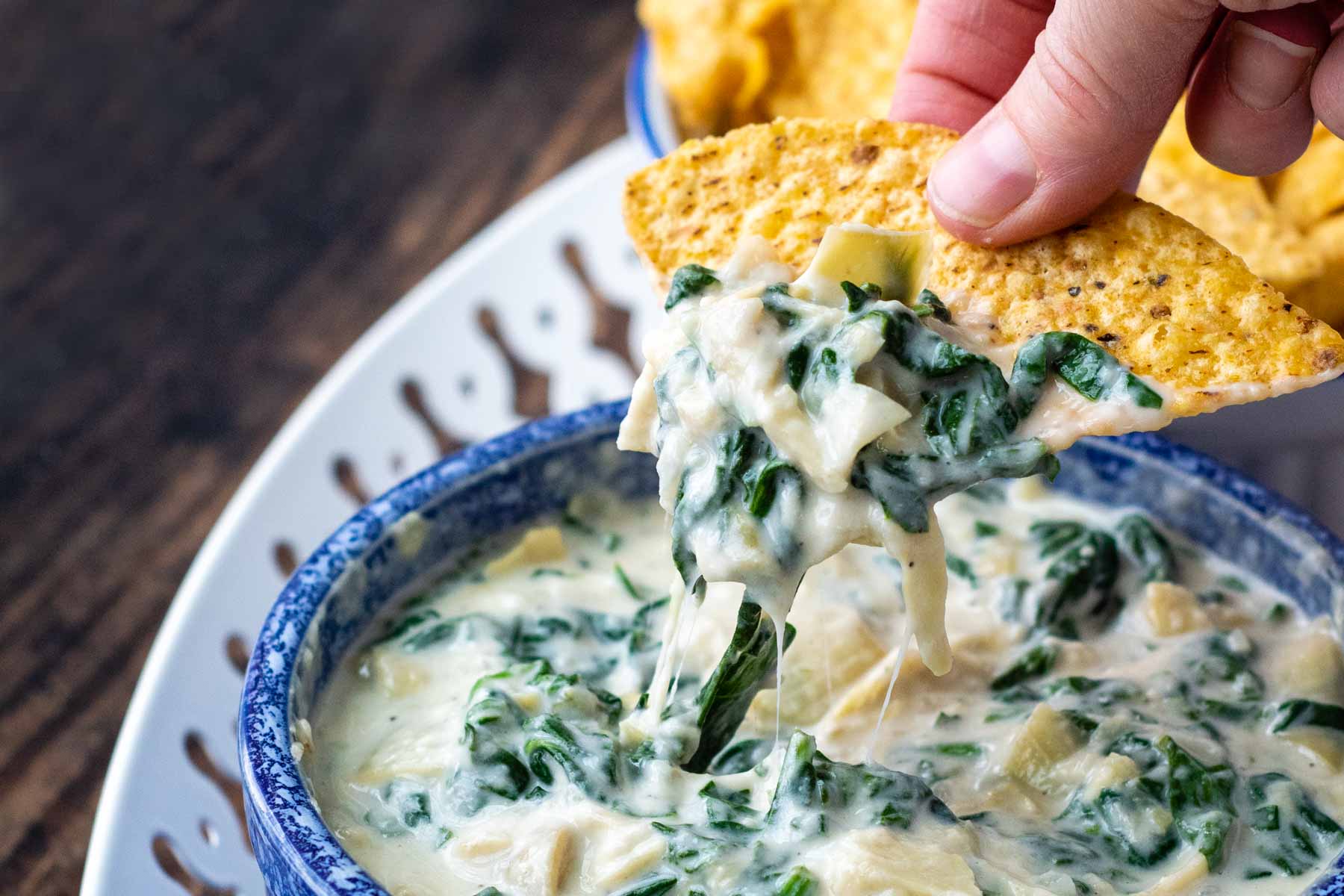 a chip dipping into spinach artichoke dip