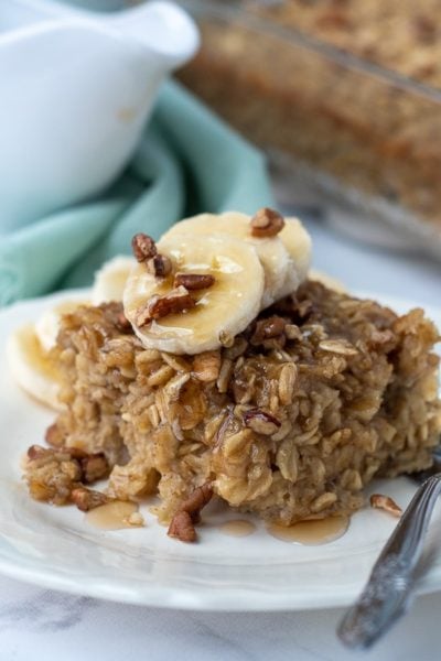 a slice of banana baked oatmeal with maple syrup dripping off