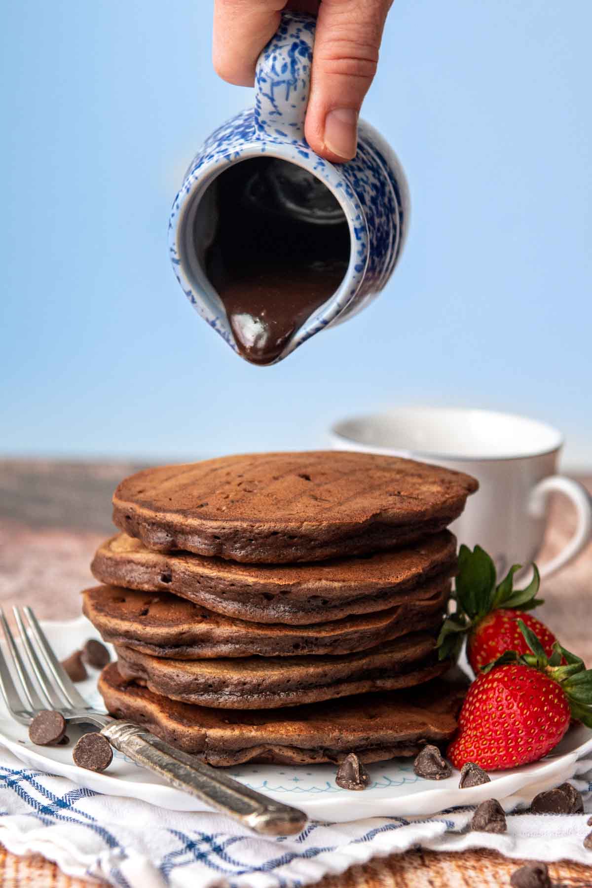 chocolate syrup about to go on a stack of chocolate pancakes