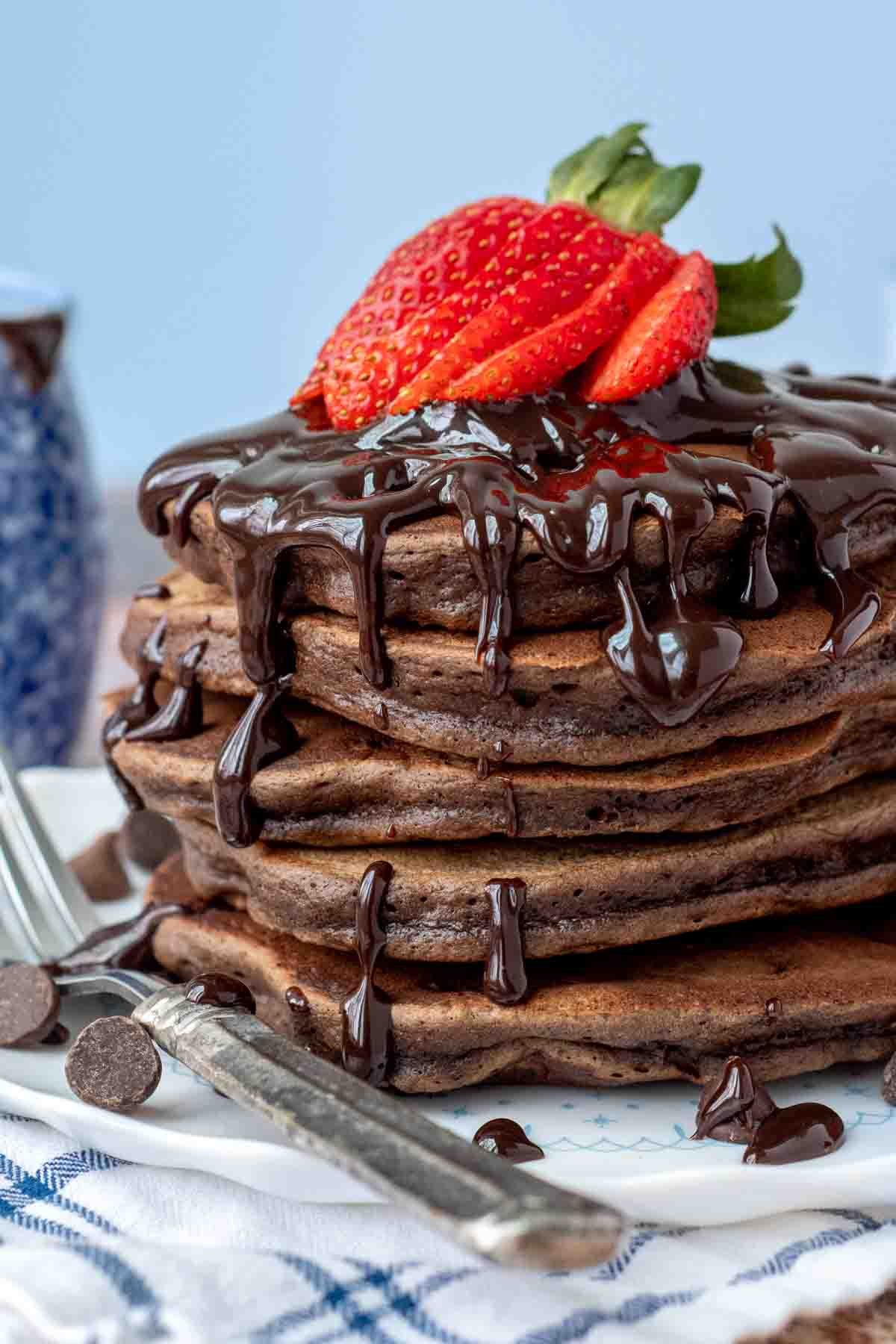 stack of double chocolate pancakes with hot fudge and strawberries on top