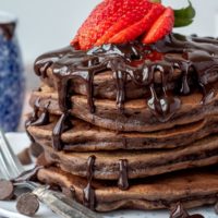 stack of double chocolate pancakes with hot fudge and strawberries on top
