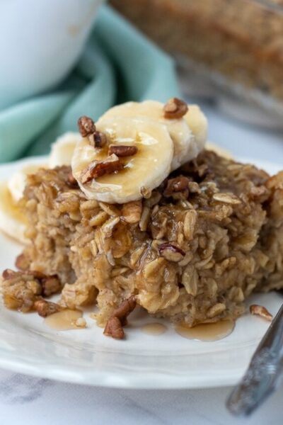 a slice of banana baked oatmeal with maple syrup dripping off