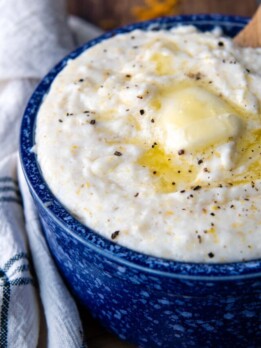 a bowl of grits with melted butter and cracked pepper on top.