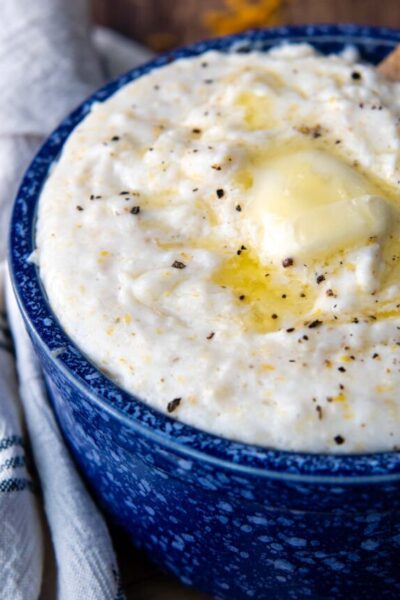 a bowl of grits with melted butter and cracked pepper on top.