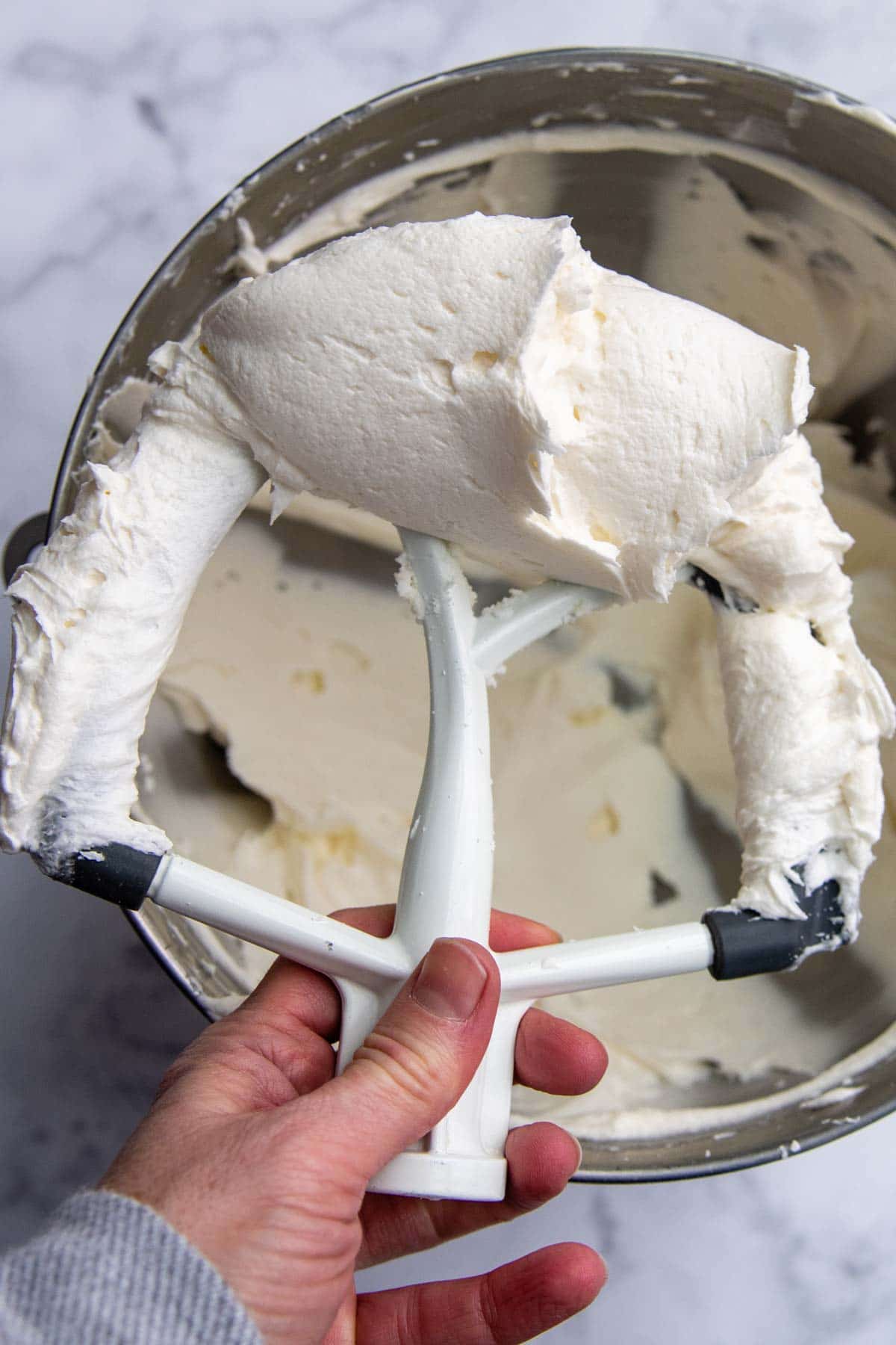 a beater holding up white buttercream frosting