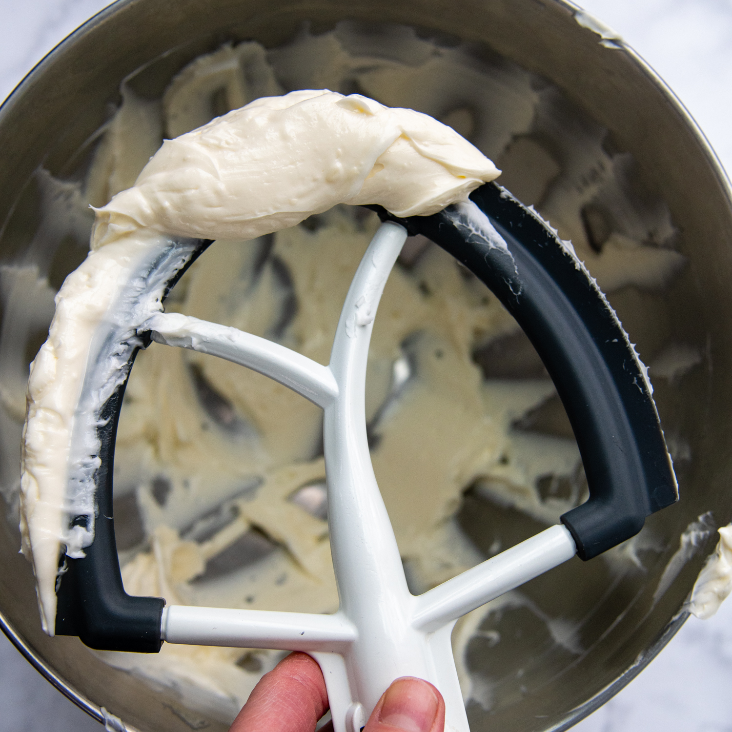 a batter being held up to show the creamy butter.