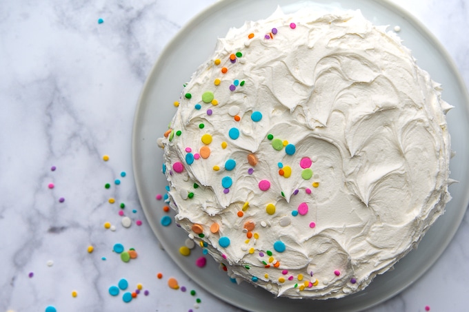 overhead shot of white cake with sprinkles falling off