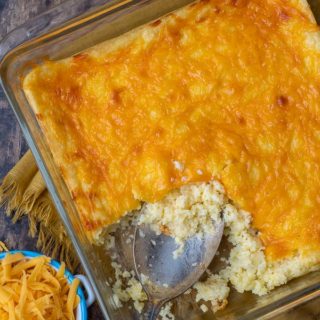overhead shot of cheese grits casserole with shredded cheese next to it