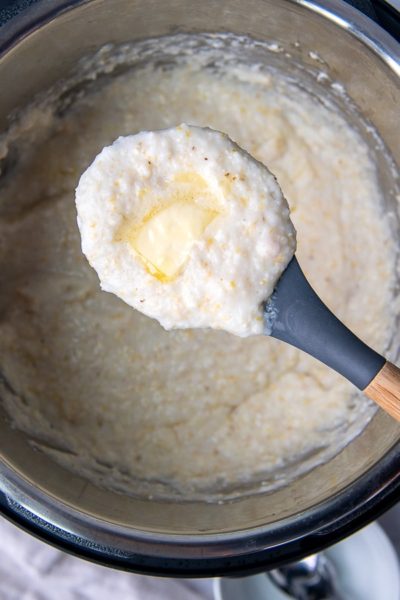 a spoon holding up a scoop of instant pot grits