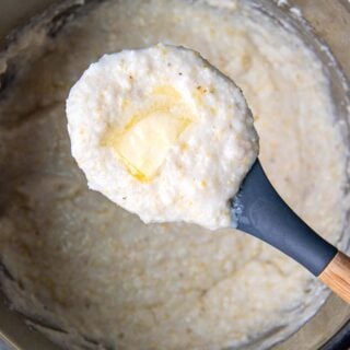 a scoop of grits with melted butter on top being held up from an instant pot.