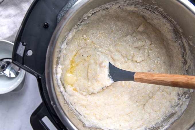 a spoon resting in an instant pot with grits inside 