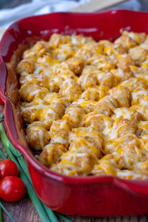 picture of tater tot casserole in a red dish with melted cheese on top